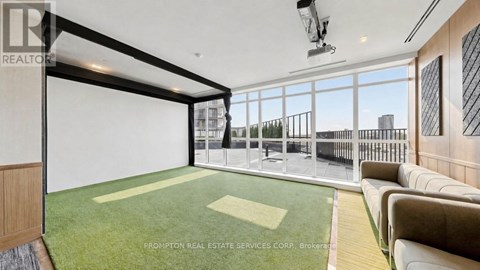 A spacious living room with a green carpet and a large window overlooking a cityscape.