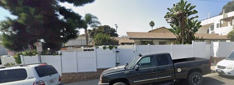 A black truck is parked in front of a white fence.