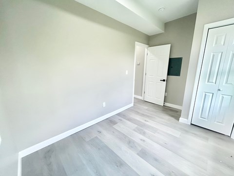 A room with a white door and a grey wall.