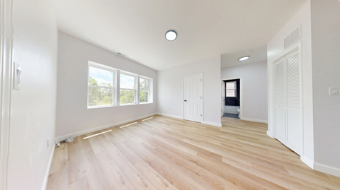 A spacious room with wooden flooring and white walls.