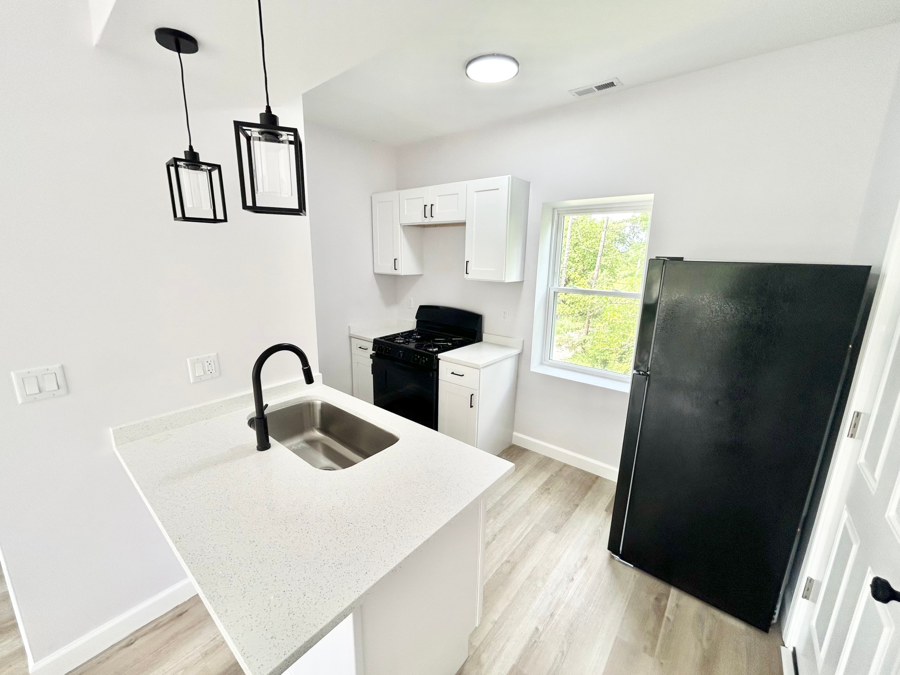 A kitchen with black appliances and white cabinets.