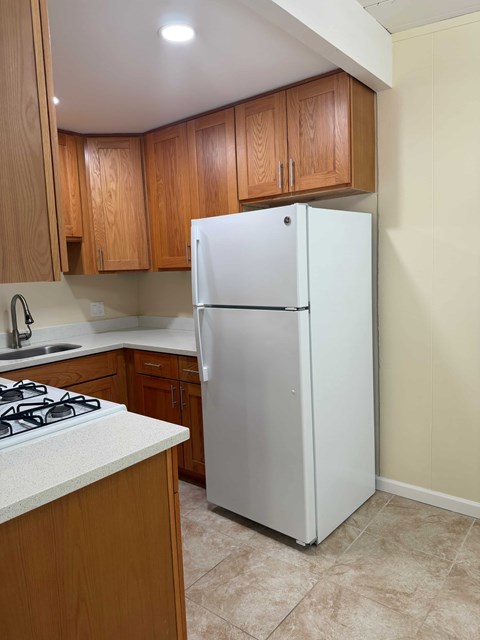 A white refrigerator in a kitchen with wooden cabinets.