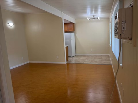 A room with wooden floors and a white refrigerator.