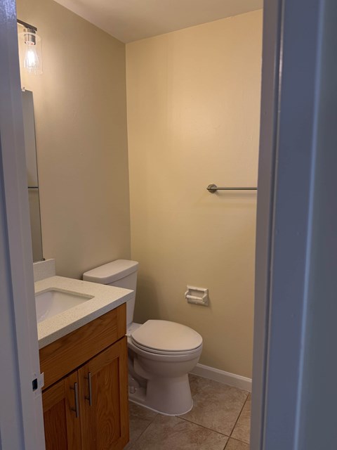 A white toilet sits in a bathroom next to a sink.
