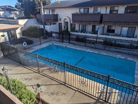 A pool surrounded by a black fence with a building in the background.