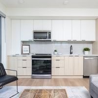 A modern kitchen with white cabinets and a black chair.