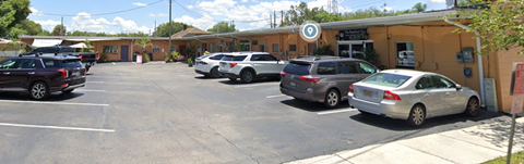 A parking lot with cars and a building with a circular logo on top.