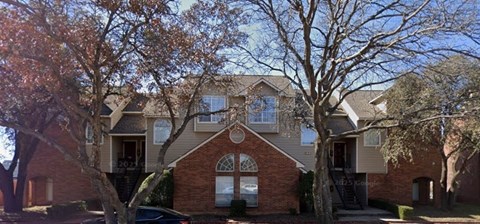 A brick house with a tree in front of it.