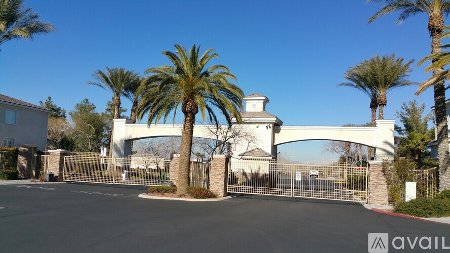 A gated entrance to a property with palm trees and a clear blue sky.