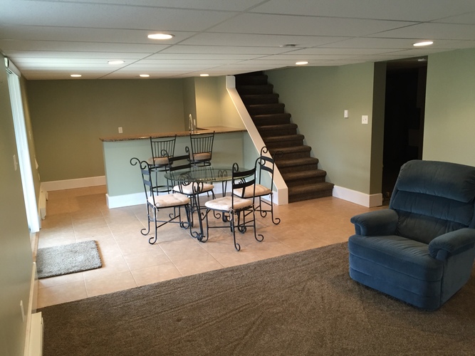 A living room with a blue chair and a table with four chairs.