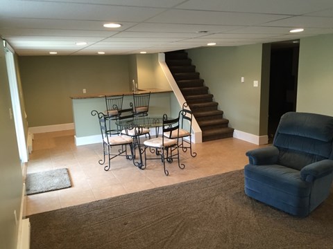 A living room with a blue chair and a table with four chairs.