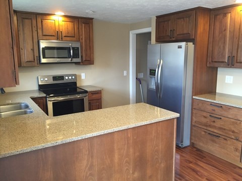 A kitchen with wooden cabinets and a granite countertop.