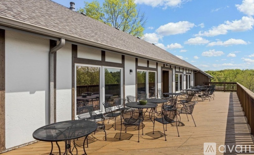A patio with a table and chairs is set up on a wooden deck.