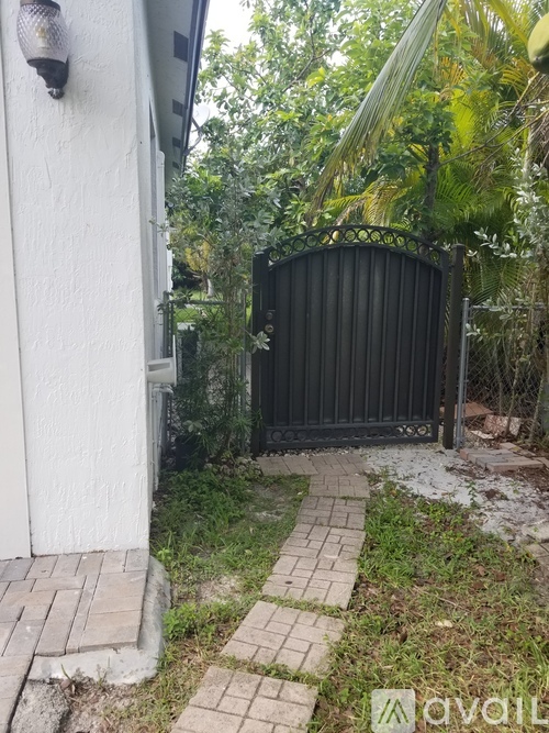 A black gate is closed and locked, blocking the way to a path.