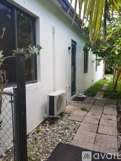 A white house with a black gate and a white air conditioner unit.