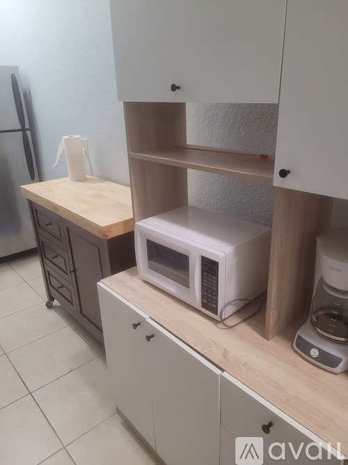 A kitchen with a refrigerator, microwave, and a coffee maker.