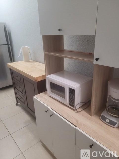 A kitchen with a refrigerator, microwave, and a coffee maker.