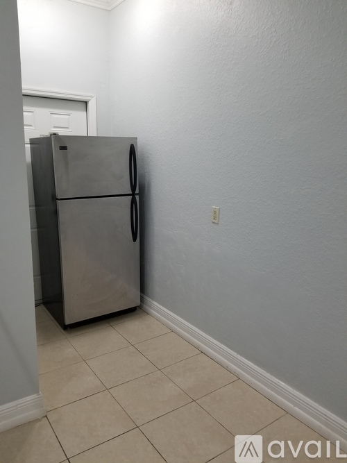 A stainless steel refrigerator in a room with white walls and tiled floor.