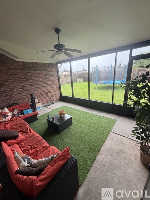 A living room with a red couch and a ceiling fan.