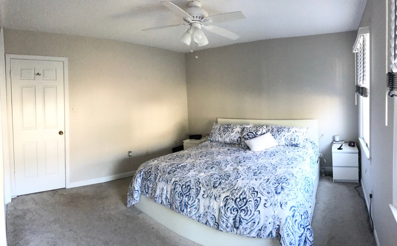 A bedroom with a bed, a ceiling fan, and a nightstand.