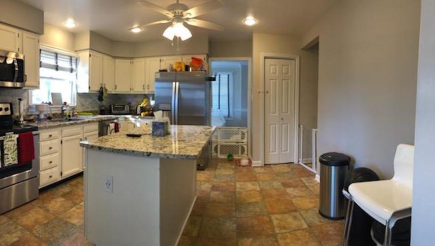 A kitchen with a refrigerator, sink, and a fan.