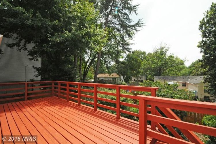 A wooden deck with a railing and trees in the background.