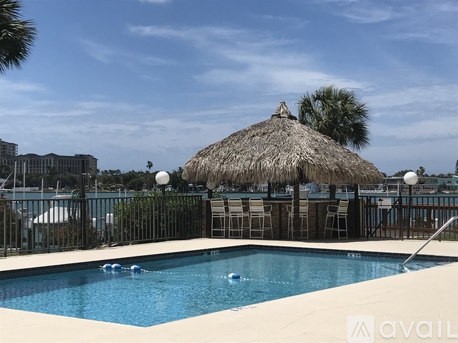 A pool with a thatched roof and chairs around it.