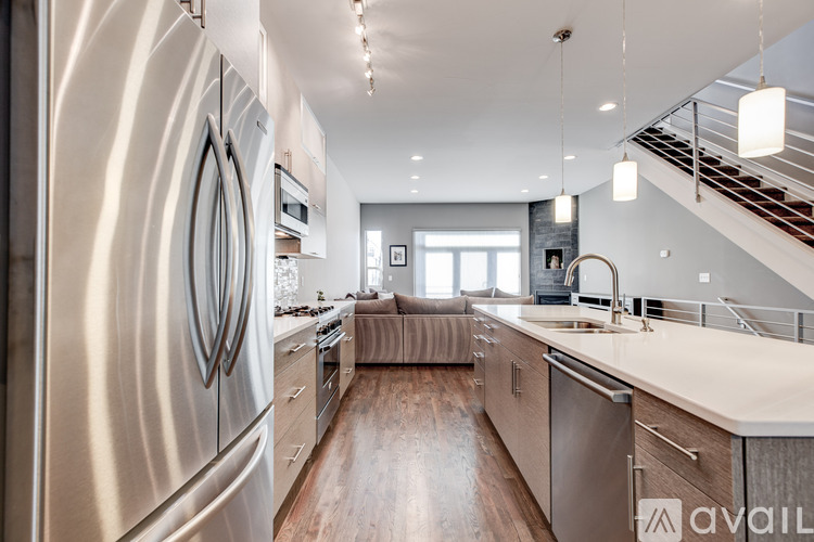 A modern kitchen with a stainless steel refrigerator and wooden floors.