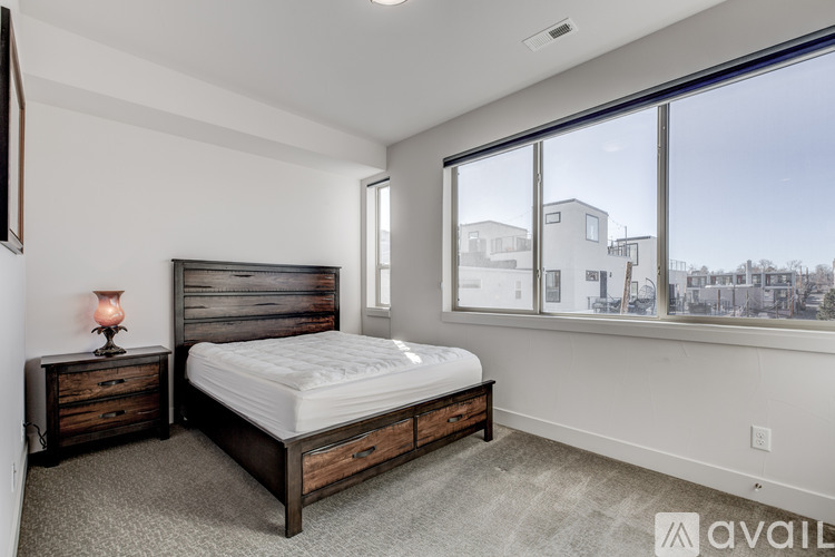 A bedroom with a large bed and a nightstand with a lamp.