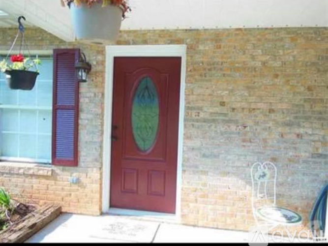 A red door with a glass window is set in a brick wall.