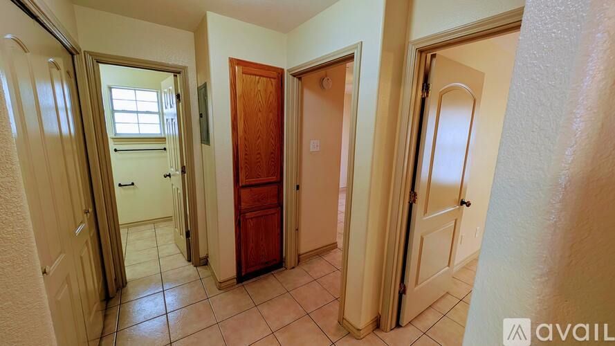 A hallway with a brown door and white walls.