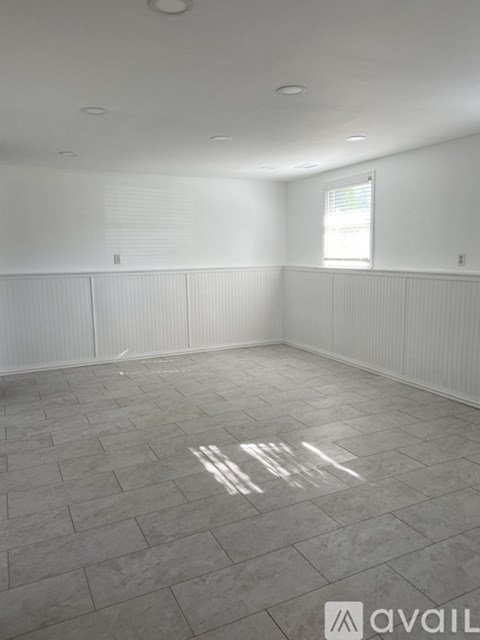 A room with a tiled floor and a window with blinds.