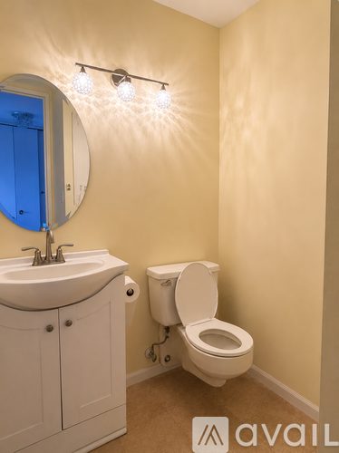 A bathroom with a toilet, sink, and mirror.