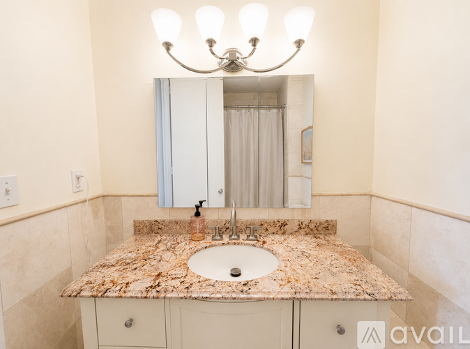 A bathroom with a granite countertop and a chandelier.