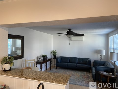 A living room with a blue couch and a ceiling fan.