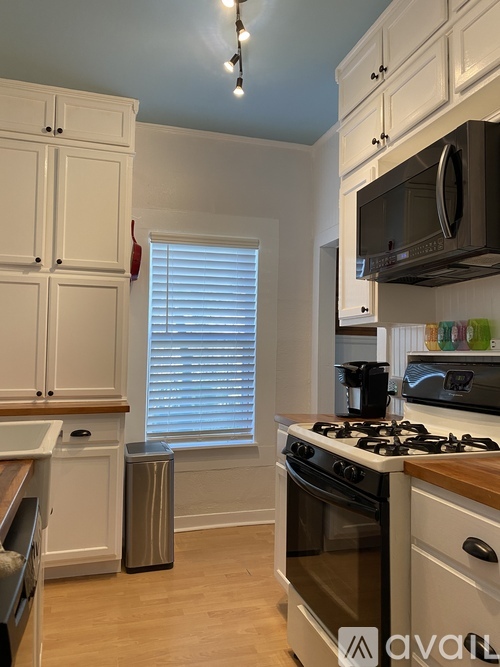 A kitchen with white cabinets and a black stove top oven.