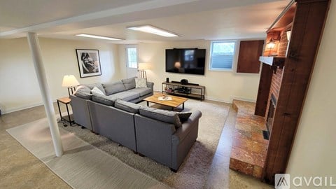 A living room with a grey couch and a television on the wall.