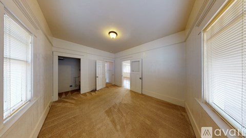 A spacious room with wooden flooring and white walls.