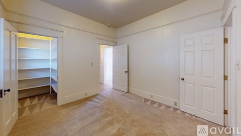 A room with white walls and a carpeted floor with a door on the right.