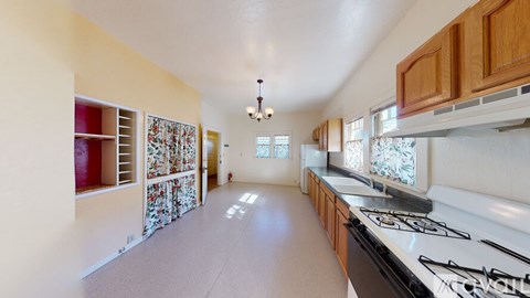 A kitchen with a white stove top oven and wooden cabinets.