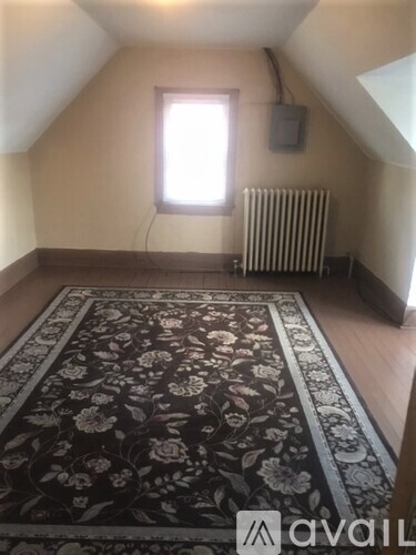 A room with a window and a radiator with a rug on the floor.