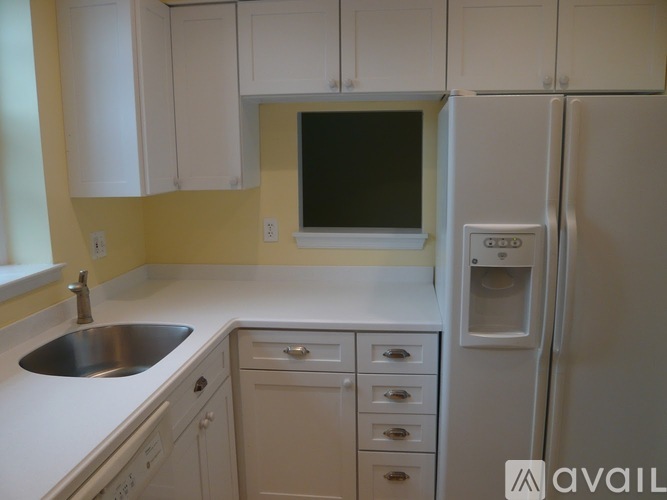 A kitchen with white cabinets and a white fridge.