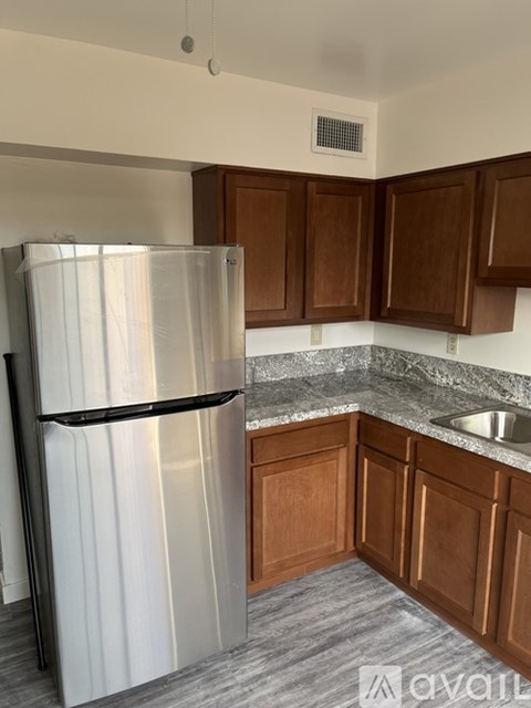 A kitchen with a stainless steel refrigerator and wooden cabinets.