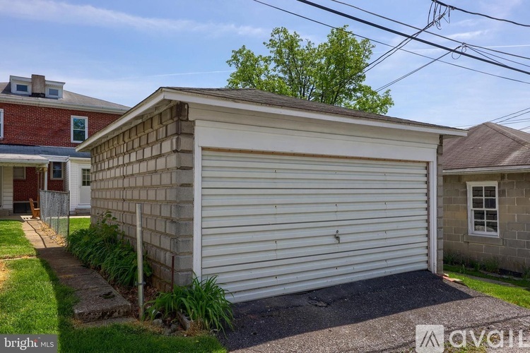 A two-car garage with a white door is situated in front of a house.