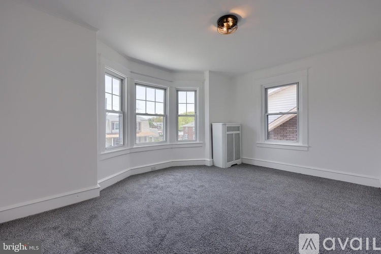 A room with a grey carpet and a window overlooking a building.