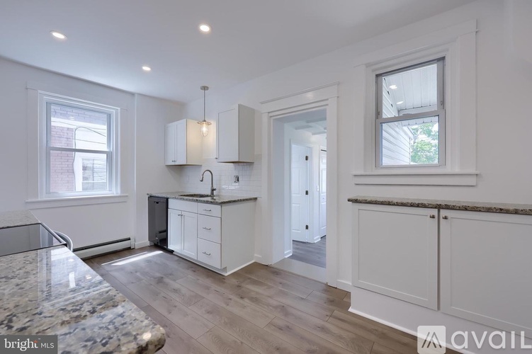 A kitchen with white cabinets and a marble countertop.