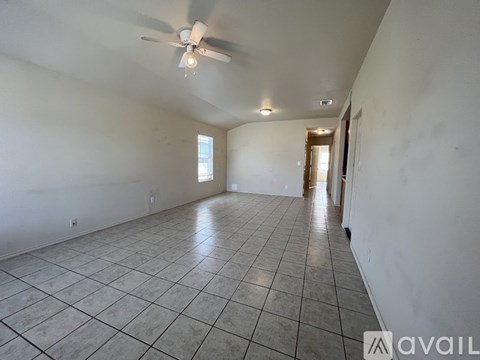 A spacious room with a tiled floor and a ceiling fan.