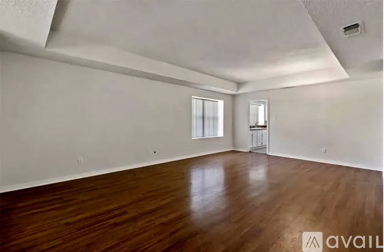 A spacious room with wooden flooring and white walls.
