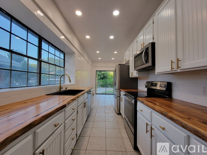 A modern kitchen with white cabinets and a wooden countertop.