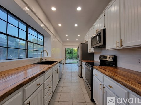 A modern kitchen with white cabinets and a wooden countertop.